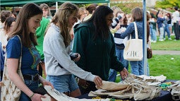 three students collect Honors College swag at outdoor campus event