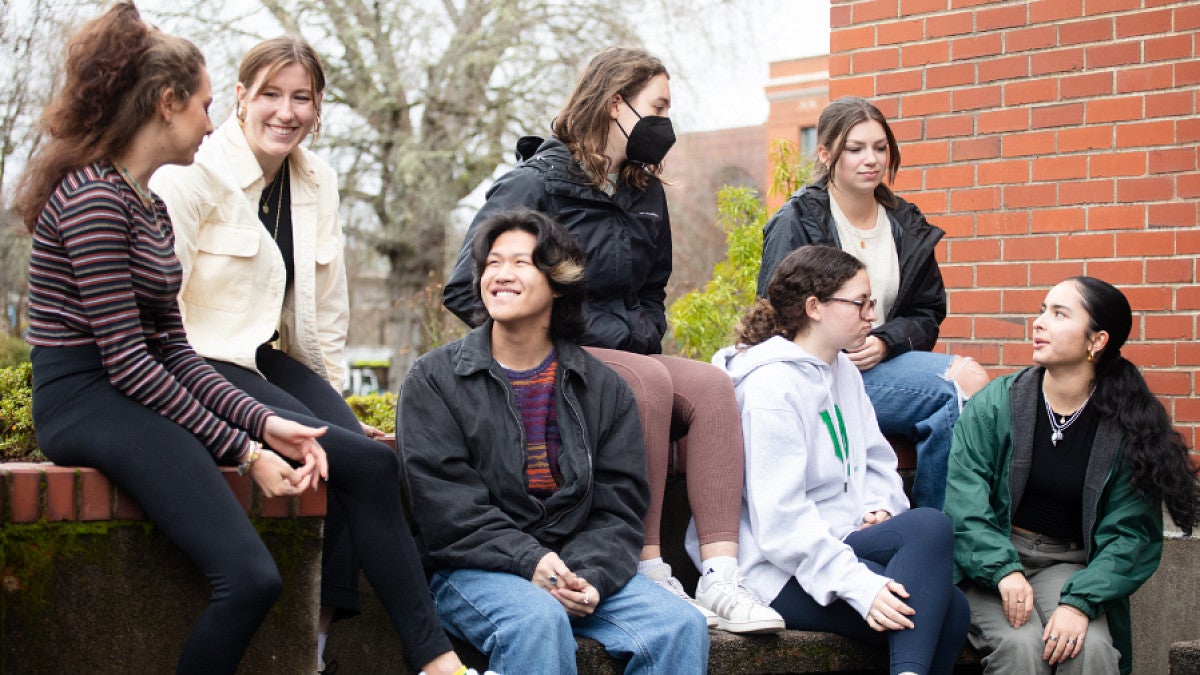 Students conversing outside a brick building in very early spring.