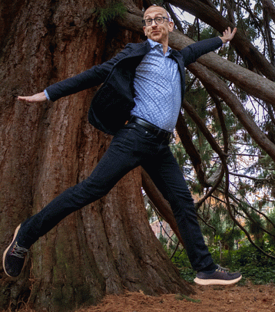 Brian McWhorter dances in front of a cedar trunk