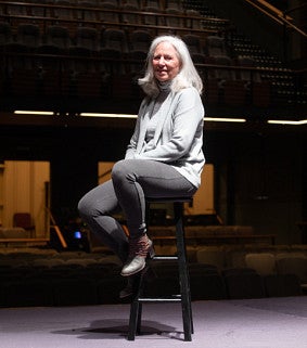 Ginerva Ralph seated on a spot-lit stage.