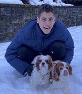 Ele Bernell crouching in the snow with two small dogs.