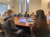 Two students, seen from behind, in a classroom setting, seated at a table in front of open laptops
